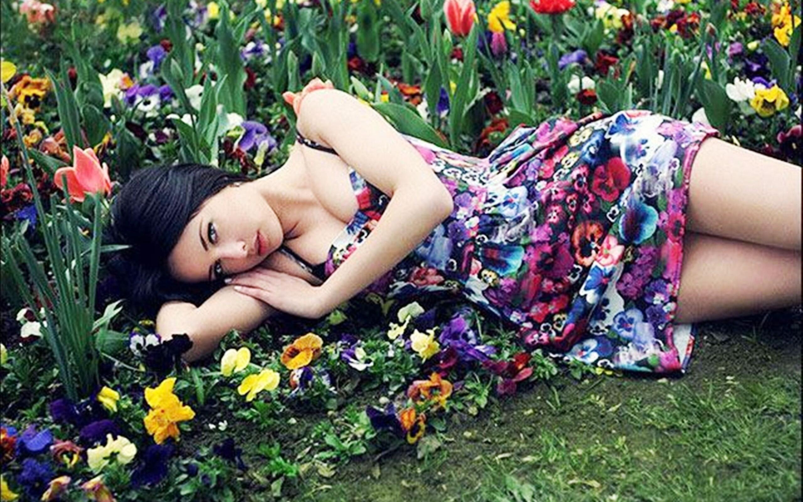 Фото девушки с силиконовой грудью на фоне цветочной клумбы