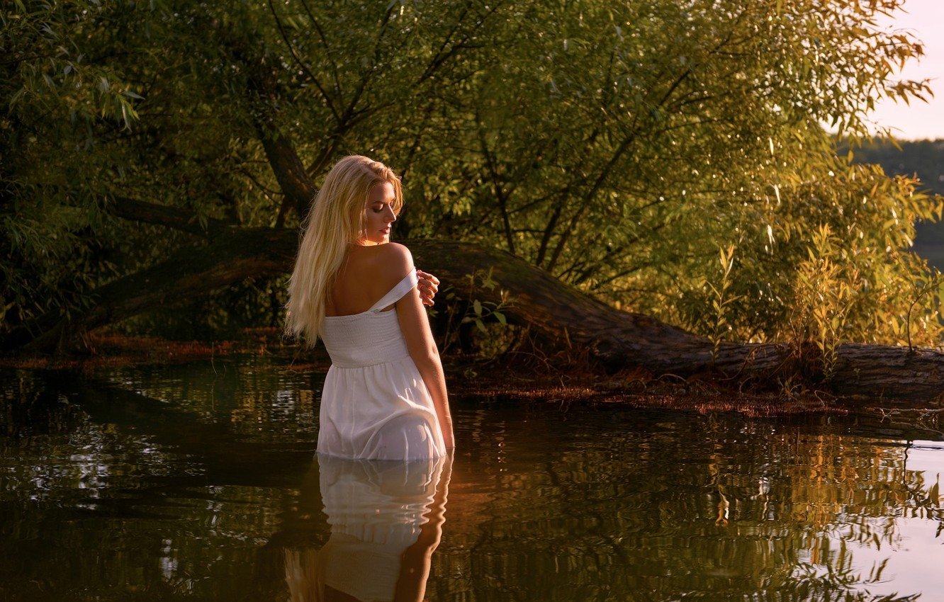 Голая девушка позирует на берегу реки