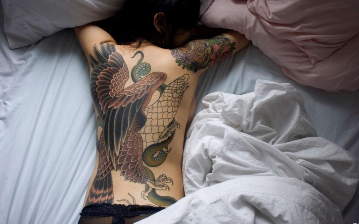 Сисястая мамка с цветными татуировками на кровати трахается с ухажером