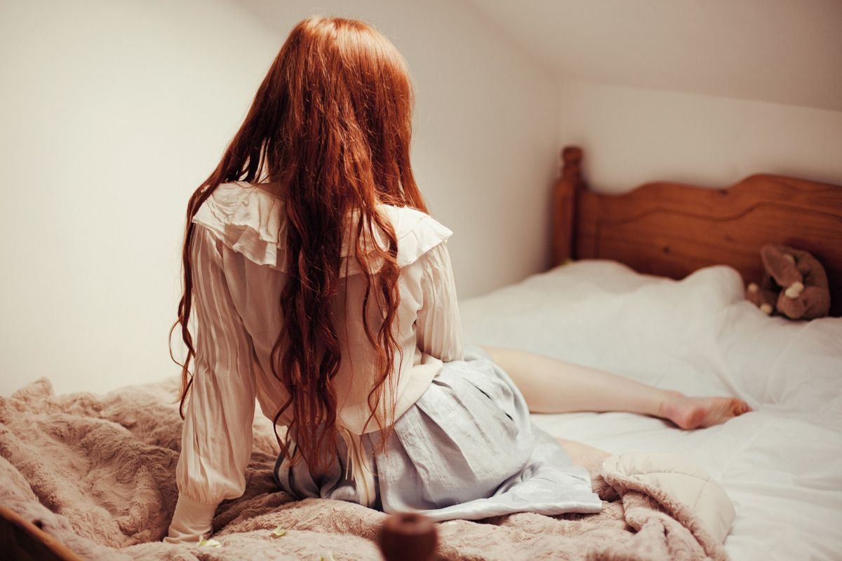 Полная дама с рыжими волосами ласкает себя пальцами на кровати