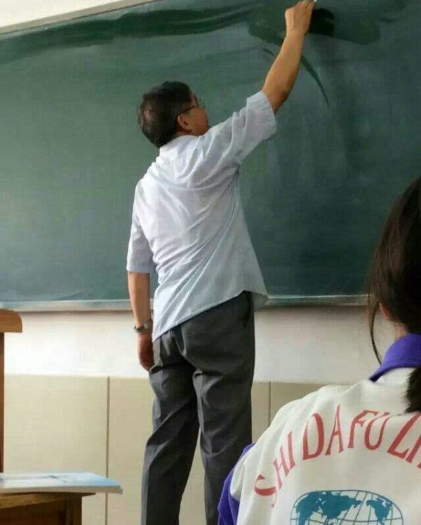 Учитель рисует на доске карту мира